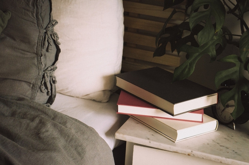 Безлад зі стосів книг та журналів на підлозі біля ліжка
